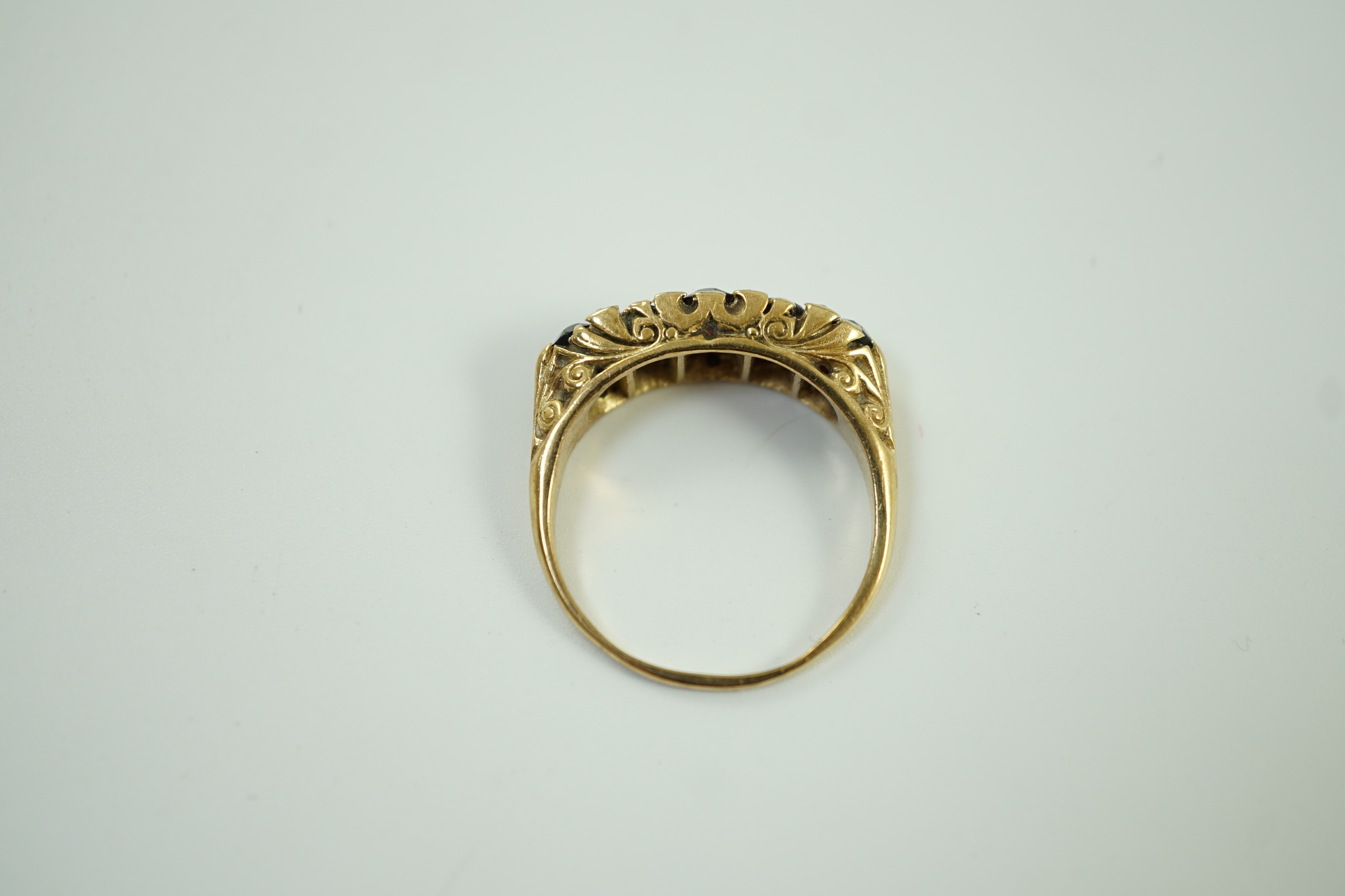 A 1960's Victorian style 9ct gold and graduated five stone garnet set half hoop ring, with diamond chip spacers, size V, gross weight 6 grams.